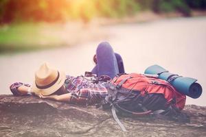 viaggiatore hipster dormire relax sulla roccia in riva al lago in viaggio di lei foto