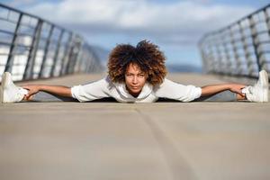 giovane donna di colore che fa stretching dopo aver corso all'aperto foto