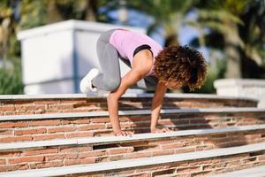 donna in forma nera che fa acrobazie di fitness in background urbano foto