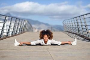 giovane donna di colore che fa stretching dopo aver corso all'aperto foto