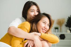 belle giovani donne asiatiche lgbt lesbica coppia felice seduta sul letto abbracciando e sorridendo insieme in camera da letto a casa. lgbt coppia lesbica insieme al chiuso concetto. passare del tempo piacevole a casa. foto