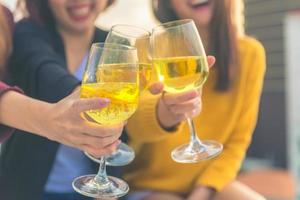 colpo all'aperto di giovani che tostano bevande a una festa sul tetto. giovani amiche asiatiche che vanno in giro con un drink. festa di festa festa di festa. festa di stile di vita adolescenziale. libertà e divertimento all'aria aperta. foto