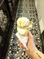 sapore di gelato alla vaniglia dessert congelato modello in cono di cialda che tiene la mano sul tavolo. foto