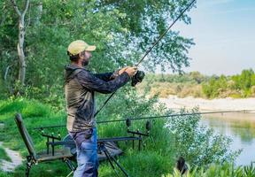 uomo adulto con la barba che fa una sessione di pesca sul fiume ebro foto