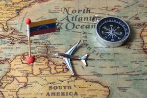 bandiera venezuela, bussola e aereo sulla mappa del mondo. foto