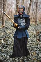 uomo che pratica kendo con spada di bambù shinai sullo sfondo della foresta foto