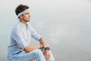 uomo seduto su un ponte di legno e guarda il riflesso dell'acqua del cielo blu foto