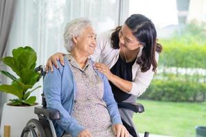 la figlia del caregiver aiuta la donna anziana anziana o anziana asiatica che si siede sulla sedia a rotelle. foto