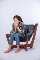 una donna che è a disagio e si siede su una sedia foto