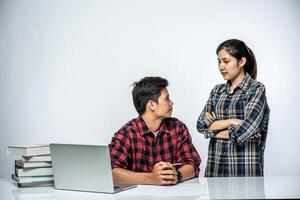 le donne insegnano agli uomini come lavorare con i laptop al lavoro. foto