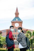 studenti maschi e femmine indossano maschere e si mettono di fronte all'università. foto