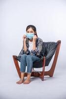 una donna scomoda seduta su una sedia e con indosso una maschera foto