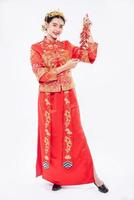 la donna indossa un abito cheongsam sorride per ricevere petardi da un parente nel capodanno cinese foto