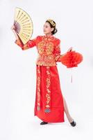 la donna indossa il vestito cheongsam promuove il ventaglio cinese e la lampada rossa sul grande evento nel capodanno cinese
