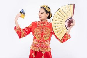 la donna indossa un abito cheongsam tiene il ventaglio cinese mostra che la carta di credito può essere utilizzata per lo shopping nel capodanno cinese
