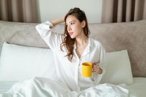 ritratto bella donna sveglia e tenendo tazza di caffè o tazza sul letto