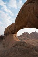 bellissimo arco naturale in arenaria. montagne in lontananza. damaraland, namibia foto