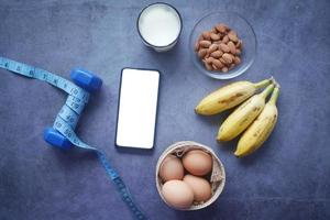 smartphone con schermo vuoto, uova, latte e mandorle sul tavolo foto