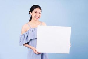 immagine di una ragazza asiatica che tiene una lavagna bianca, isolata su sfondo blu foto