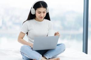 immagine di una ragazza asiatica, che usa il laptop a letto foto