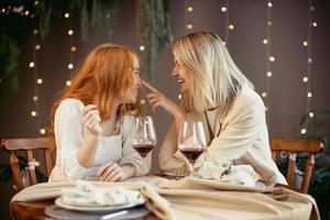 coppia lesbica a cena in un ristorante. le ragazze bevono vino e parlano foto