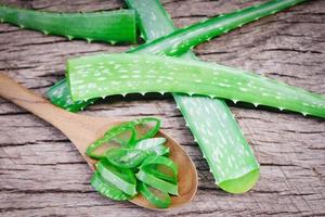 primo piano di foglie fresche di aloe vera con gel di erbe naturali e medicinali a base di erbe - fetta di pianta di aloe vera su fondo di legno rustico foto