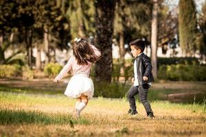 bambini nel parco. ragazzo e ragazza che giocano e corrono foto