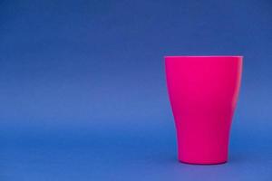 bicchiere di plastica rosa su sfondo blu foto