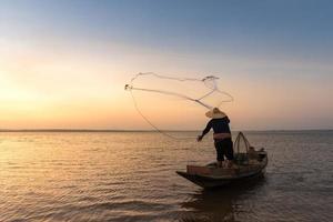 pescatore asiatico con la sua barca di legno nel fiume naturale al mattino presto prima dell'alba foto