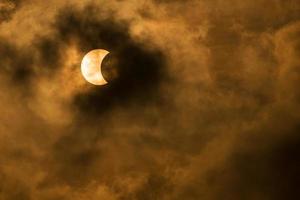 la luna che copre il sole in un'eclissi parziale con nuvole drammatiche. background scientifico, fenomeno astronomico foto