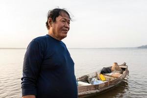 pescatore asiatico con barca di legno nel fiume naturale all'inizio dell'ora dell'alba foto