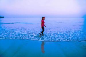 donna jogging allenamento sulla spiaggia al mattino. rilassati con la passeggiata sul mare. in estate foto