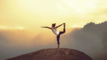 le donne asiatiche si rilassano durante le vacanze. gioca se lo yoga. sulla rupe di montagna foto