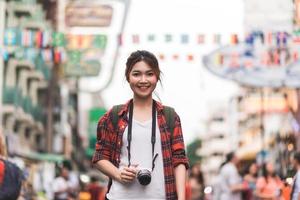 viaggiatore zaino in spalla donna asiatica viaggio a khao san road a bangkok, thailandia. felice giovane donna che trascorre le vacanze in un punto di riferimento straordinario e goditi il suo viaggio nella città tradizionale. foto