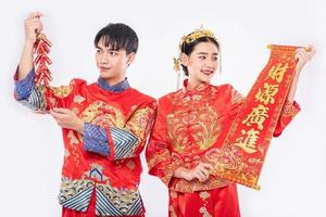 l'uomo e la donna indossano un abito cheongsam promuovono biglietti di auguri cinesi e petardi da utilizzare nel capodanno cinese