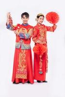 l'uomo e la donna indossano un abito cheongsam festeggiano il capodanno cinese con una lampada rossa e un petardo insieme foto