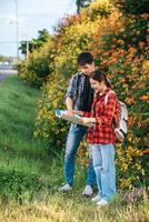 turisti uomini e donne guardano la mappa vicino ai giardini fioriti. foto