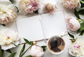 fiori di peonia, taccuino e caffè foto