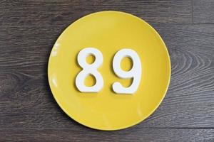il numero ottantanove su un piatto giallo. foto