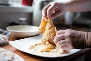 la persona impana le cotolette. preparazione di una cena tradizionale polacca. cucinare nella cucina di casa. foto