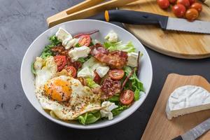 insalata perfetta durante una dieta chetogenica. pieno di grassi. uova fritte, pomodori, pancetta, lattuga e formaggio. vista dall'alto. foto