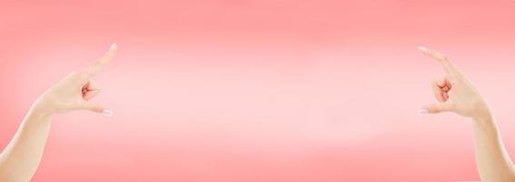 la mano femminile tiene qualcosa o punta su oggetti invisibili isolati su sfondo rosa foto