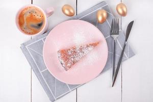 un pezzo di torta su un piatto rosa con coltello e forchetta su un tovagliolo di lino piegato foto