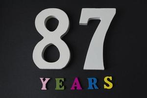 lettere e numeri di ottantasette anni su sfondo nero. foto