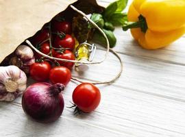 sfondo di cibo sano. cibo sano in un sacchetto di carta, verdure su uno sfondo di legno bianco foto