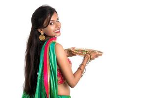 ritratto di una ragazza tradizionale indiana che tiene diya, ragazza che celebra diwali o deepavali con in mano una lampada a olio durante il festival della luce su sfondo bianco foto