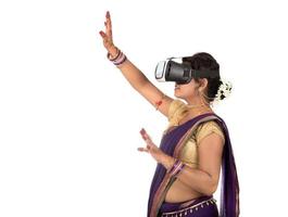 giovane donna tradizionale indiana in sari che guarda il dispositivo vr foto