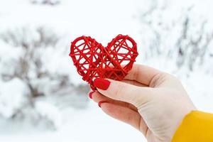 la mano tiene il cuore rosso in legno fatto da ramoscelli. foto