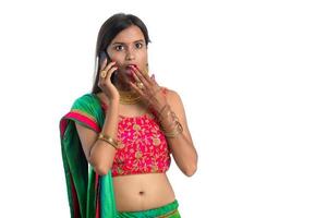 giovane ragazza indiana tradizionale che utilizza un telefono cellulare o uno smartphone isolato su uno sfondo bianco foto