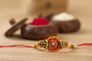 festival indiano raksha bandhan sfondo con un elegante rakhi, chicchi di riso e kumkum. un tradizionale cinturino da polso indiano che è un simbolo di amore tra fratelli e sorelle. foto